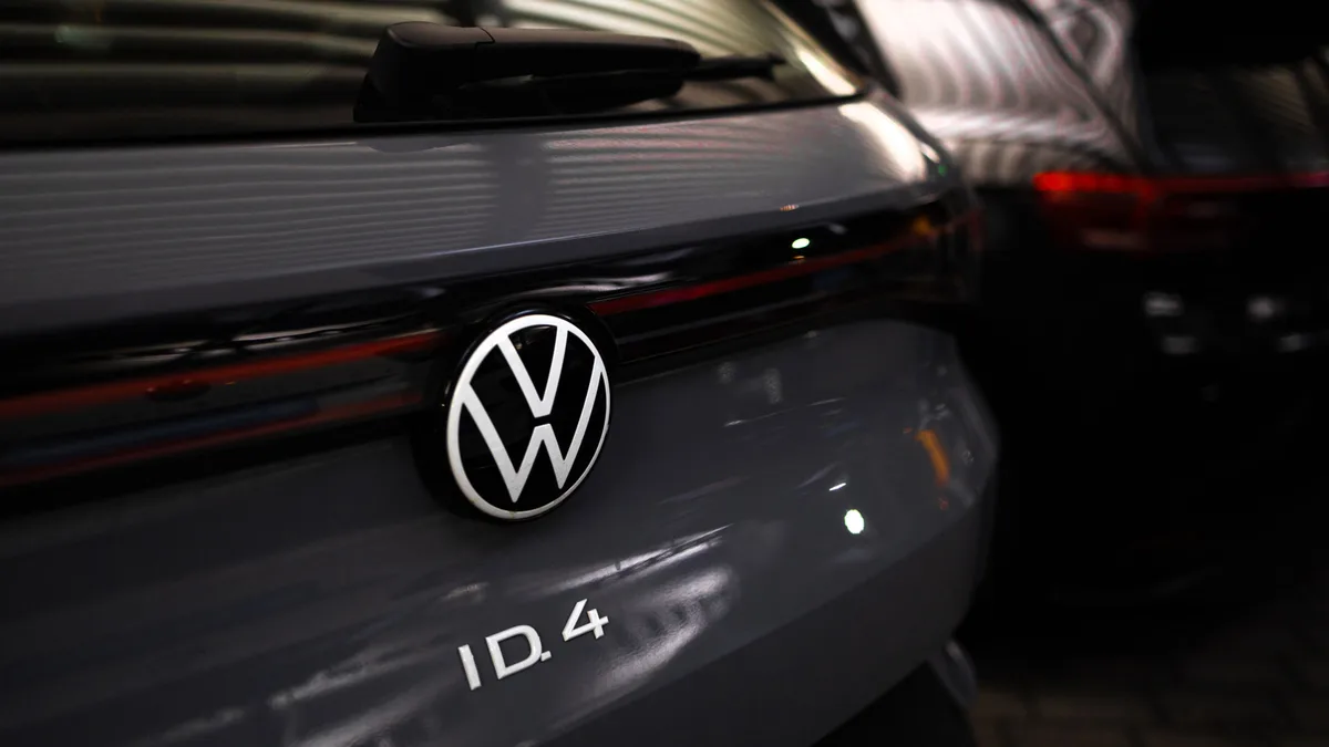 Volkswagen job cut report cover with electric car factory and software dashboard concept